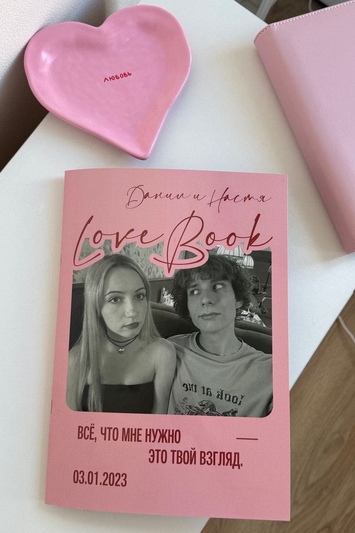Напечатанный Lovebook с обложкой «Даня и Настя» рядом с розовой тарелкой-сердцем
